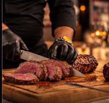 Der Küchenchef schneidet rosa gebratenes Roastbeef auf dem Holzbrett auf