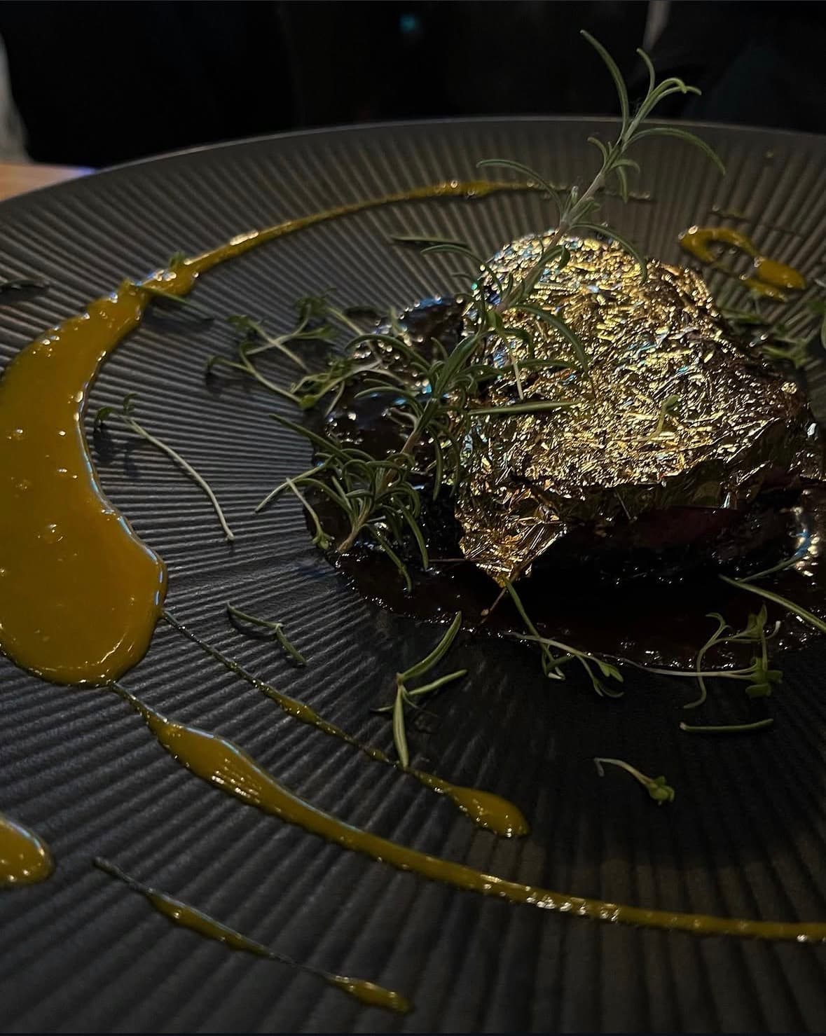 Kurzgebratenes Rinderfilet unter Blattgold mit Rosmarin und einem Spiegel aus Kräuteröl