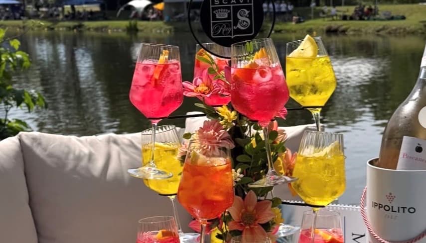 Cocktailbaum am Ufer: Aperitifs in Pink, Orange und Gelb zwischen frischen Blüten, dahinter der Fluss